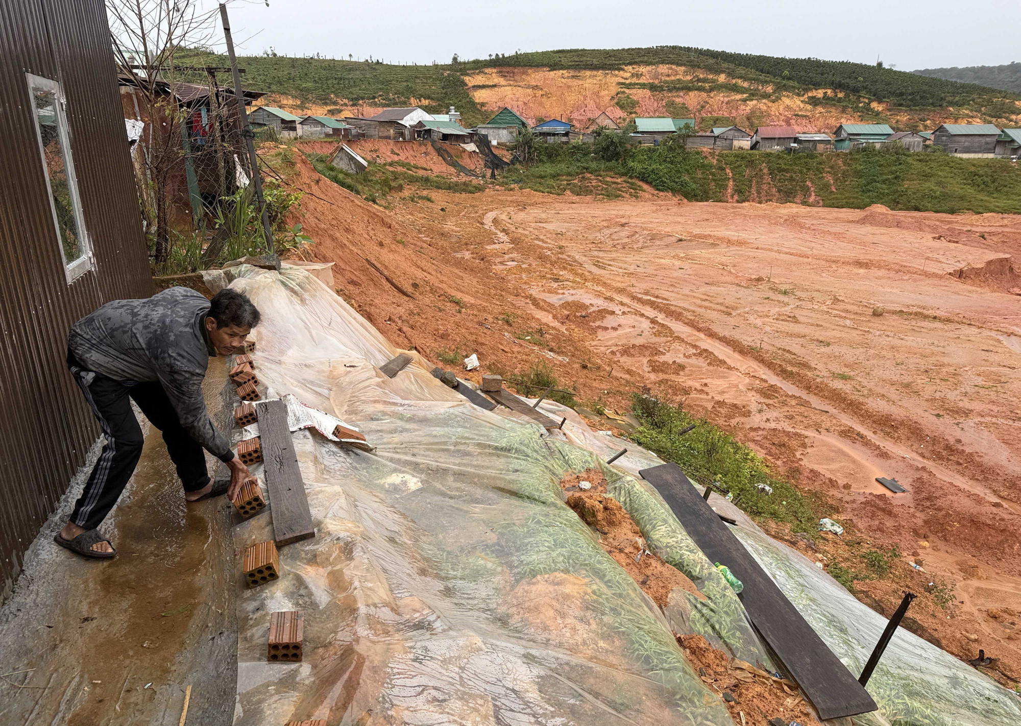 Ông Ha Trung (khu tái định cự thôn K’Nớ 5, xã Đam Rông 4) phủ nilon để ngăn nước thấm vào bờ taluy sau nhà để hạn chế sạt lở.