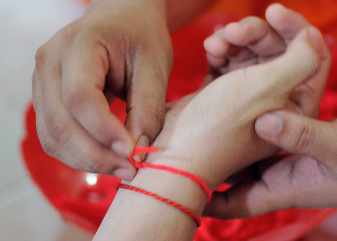 Nghi thức “cột tay” của người Khmer Nam Bộ mang ý nghĩa cầu mong sự bình an, khỏe mạnh cho những người được "cột tay. Ảnh: Lê Yến Thanh Nghi thức “Cột tay” của người Khmer Nam Bộ ảnh 1