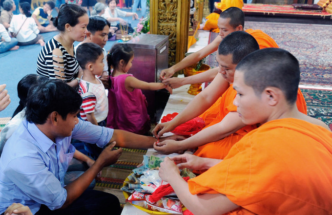 Các vị sư cột chỉ đỏ cho Phật tử Khmer Nam Bộ vào dịp Tết cổ truyền Chôl Chnăm Thmây. Ảnh: Lê Yến Thanh Nghi thức “Cột tay” của người Khmer Nam Bộ ảnh 2