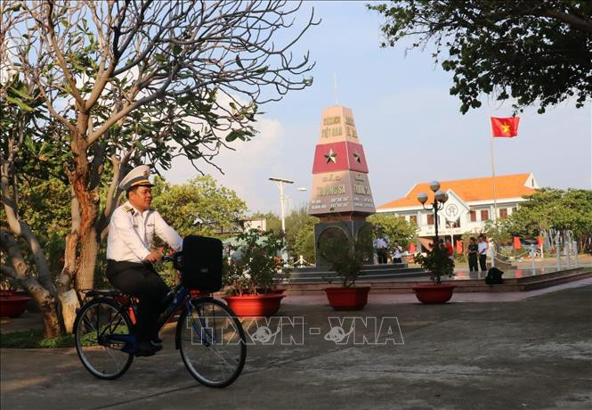 Đại tá Lê Đình Hải, Phó Lữ đoàn trưởng - Lữ đoàn 146 (vùng 4 Hải quân) đạp xe ngang qua cột mốc thị trấn Trường Sa (huyện Trường Sa, tỉnh Khánh Hoà). Ảnh: Sỹ Tuyên – TTXVN Thiêng liêng cờ Tổ quốc nơi quần đảo Trường Sa ảnh 6