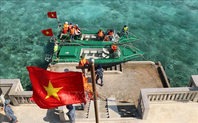 Cờ Tổ quốc tung bay phấp phới khi hai xuồng của tàu Trường Sa 571 cập mạn trên đảo Cô Lin. Ảnh: Sỹ Tuyên – TTXVN Thiêng liêng cờ Tổ quốc nơi quần đảo Trường Sa ảnh 5