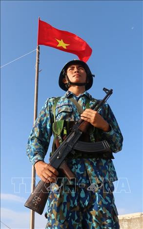 Chiến sỹ Nguyễn Xuân Quý – đảo Đá Tây A (quần đảo Trường Sa) nghiêm trang đứng gác dưới cờ Tổ quốc. Ảnh: Sỹ Tuyên – TTXVN Thiêng liêng cờ Tổ quốc nơi quần đảo Trường Sa ảnh 11