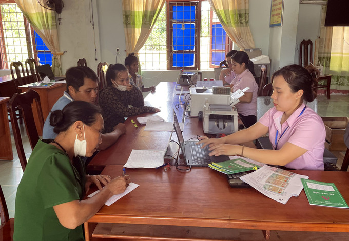 Cán bộ Phòng giao dịch Ngân hàng chính sách xã hội huyện Tuyên Hóa giải quyết thủ tục, giải ngân nguồn vốn cho vay cho người dân. Ảnh: TTXVN phát Điểm tựa vững chắc cho hộ nghèo huyện Tuyên Hóa ảnh 5