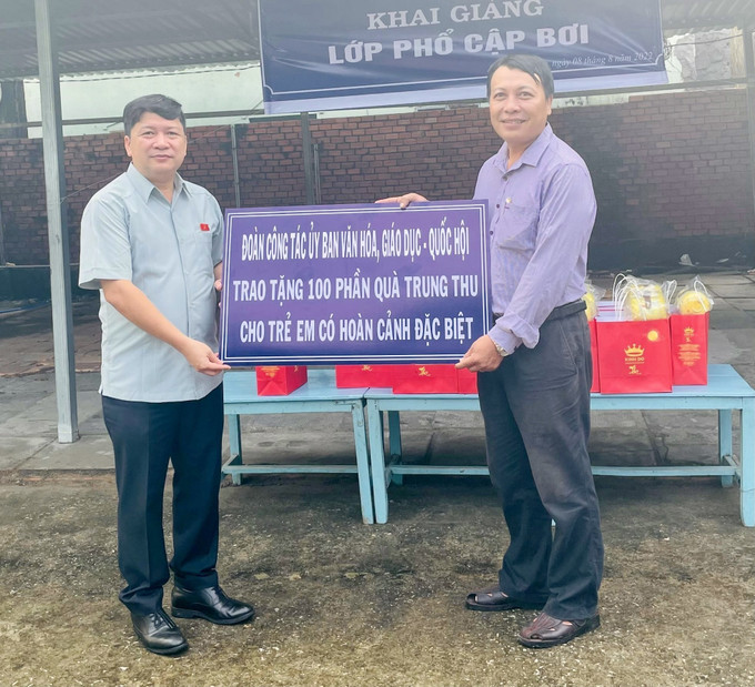 Ông Tạ Văn Hạ, Phó Chủ nhiệm Ủy ban Văn hóa-Giáo dục của Quốc (bên trái) trao 100 phần quà trung thu cho trẻ em có hoàn cảnh đặc biệt ở xã An Thạnh Trung, huyện Chợ Mới. Ảnh: Thanh Sang - TTXVN. An Giang nỗ lực thực hiện chính sách, pháp luật về phòng, chống đuối nước trẻ em ảnh 3