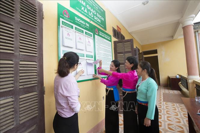 Bà con đồng bào dân tộc được cán bộ Ngân hàng Chính sách Xã hội huyện Tân Lạc hướng dẫn các chương trình vay vốn tại điểm giao dịch xã Lỗ Sơn. Ảnh: Trọng Đạt-TTXVN Hòa Bình phát triển bền vững vùng đồng bào dân tộc thiểu số ảnh 3