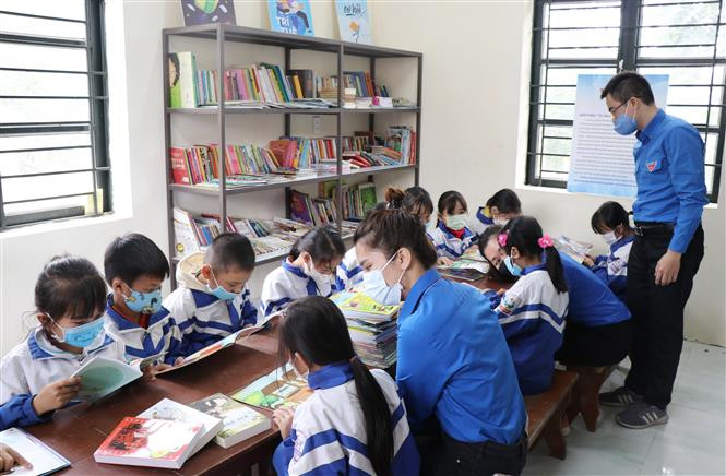 Các anh chị đoàn viên TTXVN hướng dẫn học sinh Điểm trường Văn La tra cứu thông tin bổ ích từ Tủ sách Đinh Hữu Dư. Ảnh: Hoàng Nguyên - TTXVN Đưa Tủ sách Đinh Hữu Dư về với học sinh ở ATK Định Hóa, Thái Nguyên ảnh 2