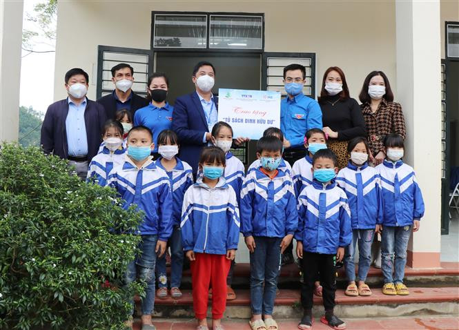 Đại diện Đoàn TNCS Hồ Chí Minh TTXVN trao tặng Tủ sách Đinh Hữu Dư cho giáo viên, học sinh Điểm trường Văn La. Ảnh: Hoàng Nguyên - TTXVN Đưa Tủ sách Đinh Hữu Dư về với học sinh ở ATK Định Hóa, Thái Nguyên ảnh 1