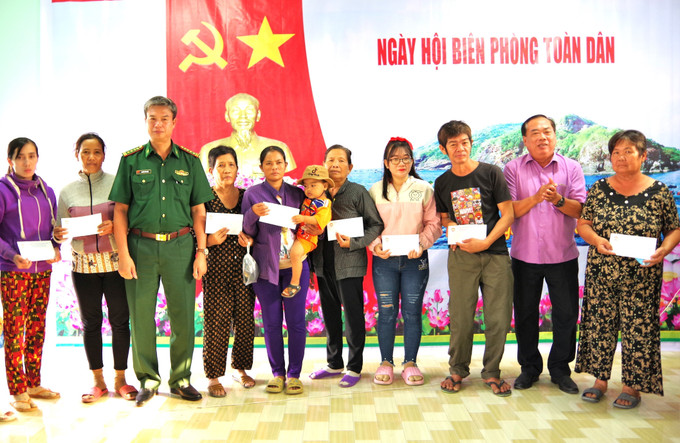 Đại diện lãnh đạo Bộ đội Biên phòng Cà Mau và Ủy ban Mặt trận Tổ quốc Việt Nam tỉnh Cà Mau trao quà cho các gia đình chính sách, hộ nghèo tại Ngày hội. Ảnh: TTXVN phát Tổ chức điểm ''Ngày hội Biên phòng toàn dân'' tại xã Tân Tiến, Cà Mau ảnh 1