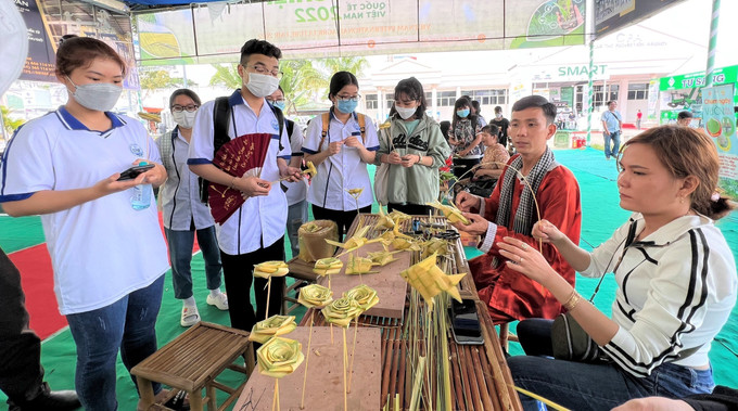Các bạn trẻ giao lưu hoạt động xếp lá dừa. Ảnh: TTXVN phát Đắm mình trong văn hóa ẩm thực, nghệ thuật dân gian tại "Ngày hội lá” ảnh 1