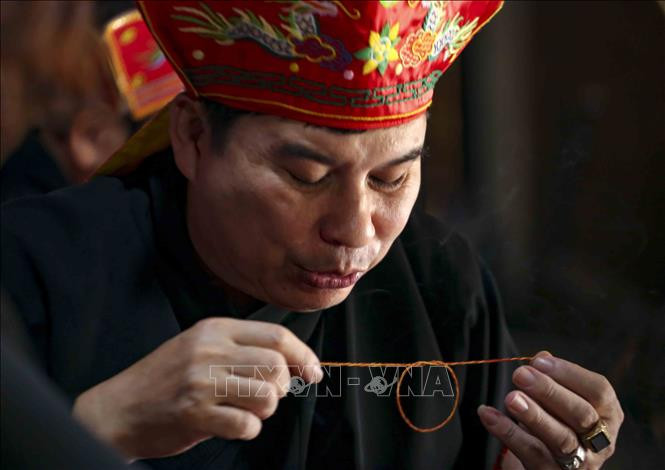 Thầy Mo thực hiện nghi lễ buộc chỉ cổ tay cầu may mắn và sức khỏe cho mọi người tại Lễ Mát nhà của đồng bào Mường (Hòa Bình). Ảnh: Tuấn Đức – TTXVN Các hoạt động tại Tuần "Đại đoàn kết các dân tộc - Di sản Văn hóa Việt Nam" năm 2021 ảnh 5