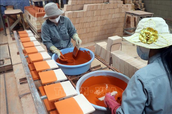 Công đoạn tráng men từng viên ngói trước khi đưa vào lò nung. Ảnh: Đỗ Trưởng – TTXVN Thừa Thiên - Huế: Người “giữ lửa” lò ngói gốm men Cung đình ảnh 7