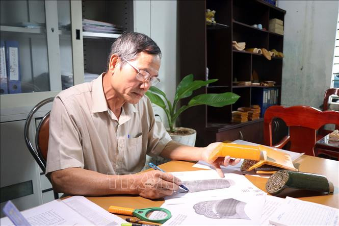 Ông Đặng Uyển nghiên cứu phục chế những viên ngói cổ. Ảnh: Đỗ Trưởng – TTXVN Thừa Thiên - Huế: Người “giữ lửa” lò ngói gốm men Cung đình ảnh 1