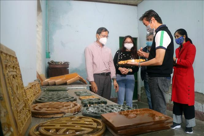 Ông Đặng Uyển (trái) giới thiệu sản phẩm ngói men Cung đình thanh lưu ly và hoàng lưu ly tới khách hàng. Ảnh: Đỗ Trưởng – TTXVN Thừa Thiên - Huế: Người “giữ lửa” lò ngói gốm men Cung đình ảnh 5