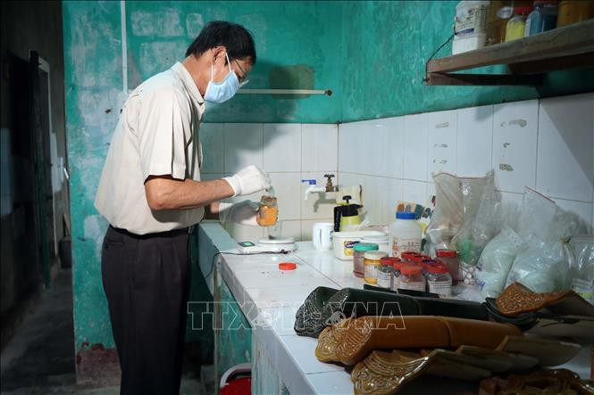 Ông Đặng Uyển pha chế bài men bí truyền để tạo lên những viên ngói Cung đình. Ảnh: Đỗ Trưởng – TTXVN Thừa Thiên - Huế: Người “giữ lửa” lò ngói gốm men Cung đình ảnh 3
