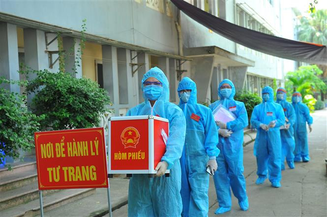 Lực lượng chức năng mang hòm phiếu đến từng phòng để cử tri thực hiện quyền bầu cử, tại đơn vị bầu cử số 7, Khu cách ly trong Trường Đại học Thể dục Thể thao, phường Trang Hạ, thị xã Từ Sơn. Ảnh: Minh Đức - TTXVN Ngày bầu cử đặc biệt tại Bắc Ninh ảnh 9