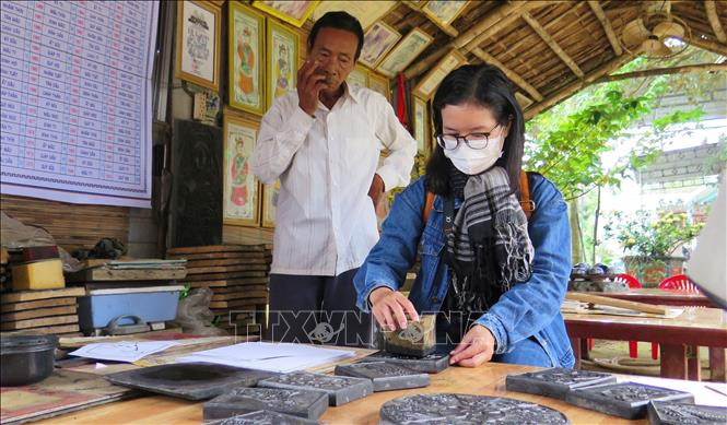 Nhiều người dân và du khách về làng Sình để trải nghiệm các công đoạn làm tranh dân gian truyền thống. Ảnh: Tường Vi – TTXVN Tết Nhâm Dần 2022: Độc đáo tranh dân gian làng Sình ảnh 1