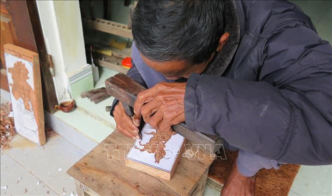 Nghệ nhân Kỳ Hữu Phước khắc mộc bản để in tranh. Ảnh: Tường Vi – TTXVN Tết Nhâm Dần 2022: Độc đáo tranh dân gian làng Sình ảnh 3