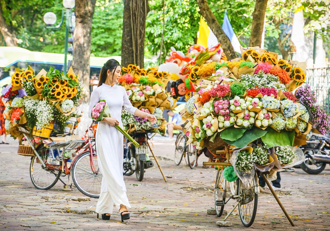 Thiếu nữ Hà Nội bên những xe hoa trên đường Phan Đình Phùng. Ảnh: Khánh Hoà – TTXVN Hà Nội đẹp dịu dàng trong tiết Thu ảnh 13