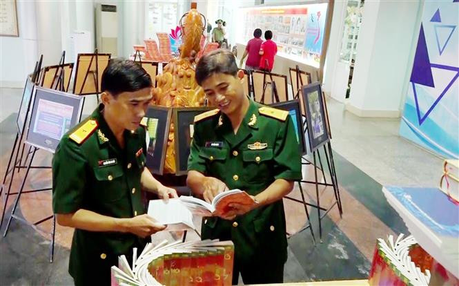 Thiếu tá Nguyễn Văn Ca Răn (bêntrái) tại triển lãm sách chuyên đề về học tập và làm theo tư tưởng, đạo đức, phong cách Hồ Chí Minh tại thành phố Long Xuyên, tỉnh An Giang. Ảnh: TTXVN phát 75 năm Thi đua ái quốc: Học Bác từ những điều giản dị nhất ảnh 1