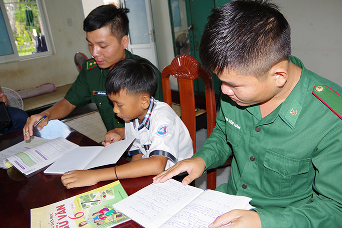 Chiến sĩ Đồn Biên phòng Phú Mỹ, huyện Giang Thành (Kiên Giang) hướng dẫn “con nuôi biên phòng” Phạm Quốc Sỹ học tập. Ảnh: Lê Sen Chiến sĩ Đồn Biên phòng Phú Mỹ, huyện Giang Thành (Kiên Giang) hướng dẫn “con nuôi biên phòng” Phạm Quốc Sỹ học tập. Ảnh: Lê Sen