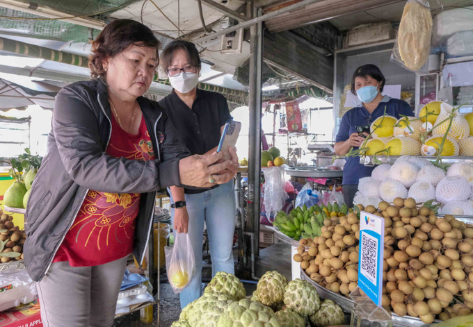 Người dân sử dụng điện thoại thông minh để thanh toán tiền mua bán hàng hóa ở chợ An Thới, quận Bình Thủy, thành phố Cần Thơ. Ảnh: Thanh Liêm – TTXVN Cần Thơ có chợ đầu tiên thanh toán không dùng tiền mặt ảnh 4