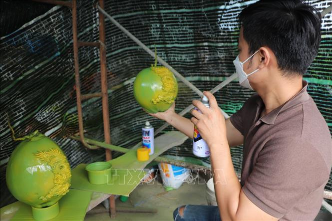 Anh Trần Minh Nhựt sơn trên trái dừa. Ảnh: Thanh Bình-TTXVN Long An: Niềm đam mê khắc họa trái dừa dịp Tết ảnh 2