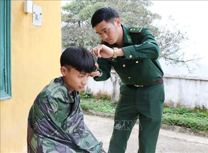 Trung úy Dì A De, Đội trưởng Đội Ma túy Đồn Biên phòng Thu Lũm cắt tóc cho cháu Mạ Đức Mạnh. Ảnh: Hoàng Thùy Oanh – TTXVN Tiếp bước em đến trường nơi vùng cao biên giới tỉnh Lai Châu (Bài 1) ảnh 2