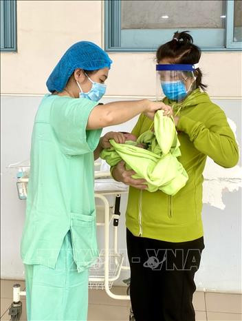 Bệnh nhân nhiễm COVID-19 được nhân viên điều dưỡng Bệnh viện Trung ương Huế hướng dẫn chăm sóc tận tình. Ảnh: Mai Trang-TTXVN Hành trình sinh tử của mẹ con sản phụ mắc COVID-19 ảnh 3