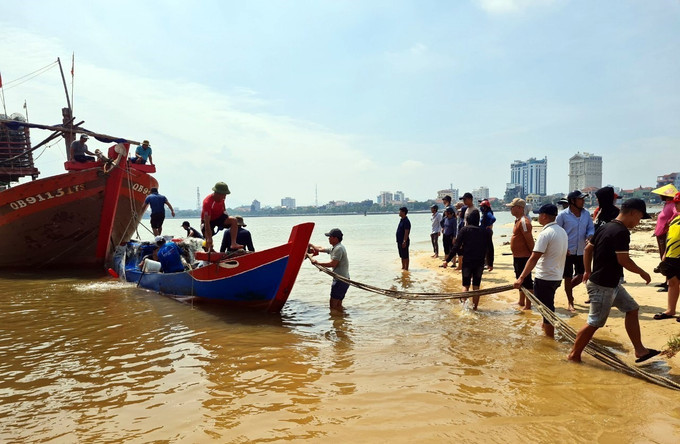 Người dân địa phương hỗ trợ lai dắt và trục vớt thuyền bị chìm của ngư dân đưa vào bờ. Ảnh: TTXVN phát Chìm thuyền trên biển, hai ngư dân tự bơi vào bờ ảnh 1