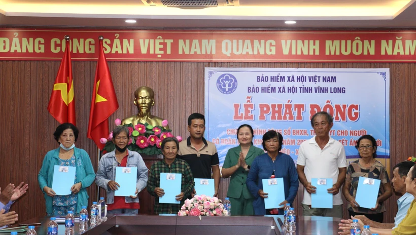 Trao thẻ bảo hiểm y tế cho người dân có hoàn cảnh khó khăn. Ảnh: Lê Thúy Hằng - TTXVN