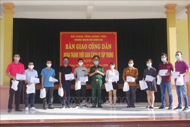 Trao giấy chứng nhận hoàn thành cách ly tập trung cho các công dân về từ Cộng hòa Nam Phi. Ảnh: Đinh Tuấn - TTXVN