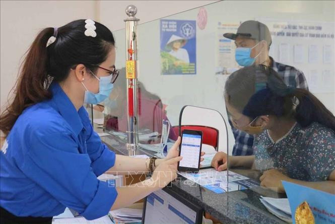 Cán bộ Bảo hiểm xã hội hướng dẫn người dân cài đặt ứng dụng VssID. Ảnh: TTXVN phát 