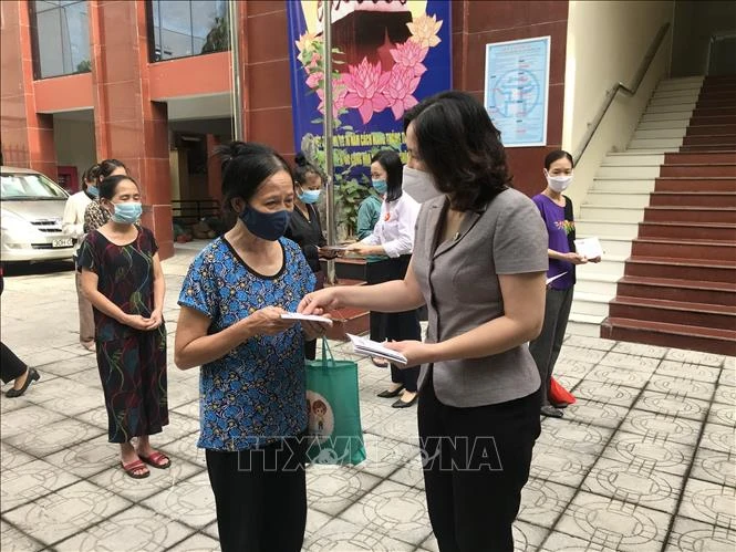 Chủ tịch Hội Liên hiệp phụ nữ thành phố Hà Nội Lê Kim Anh trao suất quà cho nữ lao động di cư gặp khó khăn. Ảnh: TTXVN phát 