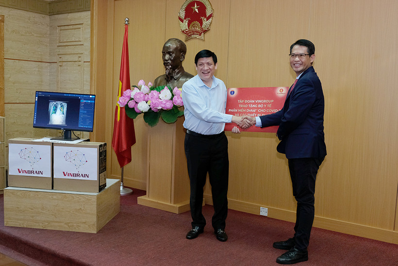 Quyền Bộ trưởng Bộ Y tế Nguyễn Thanh Long nhận biểu trưng phần mềm DrAid™ cùng các thiết bị đi kèm để hỗ trợ đánh giá tiên lượng trong điều trị COVID-19 từ ông Trương Quốc Hùng, Tổng giám đốc VinBrain. ncov.moh.gov.vn 