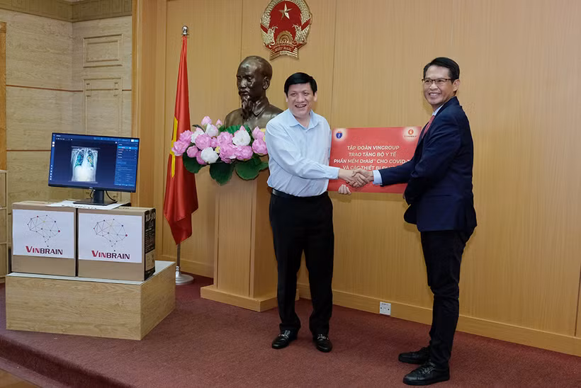 Quyền Bộ trưởng Bộ Y tế Nguyễn Thanh Long nhận biểu trưng phần mềm DrAid™ cùng các thiết bị đi kèm để hỗ trợ đánh giá tiên lượng trong điều trị COVID-19 từ ông Trương Quốc Hùng, Tổng giám đốc VinBrain. ncov.moh.gov.vn 