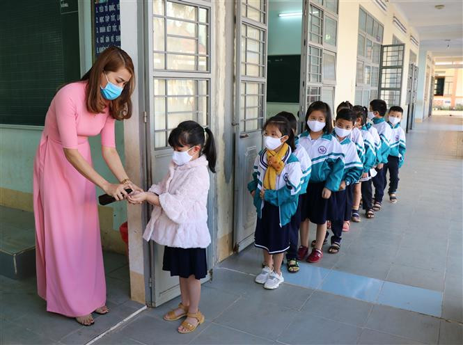  Xịt nước rửa tay kháng khuẩn cho học sinh trước khi vào lớp. Ảnh: Hồng Điệp - TTXVN 