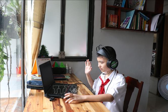 Học sinh Trường THCS Tương Bình Hiệp, thành phố Thủ Dầu Một, chào cô giáo và các bạn cùng lớp trên lớp học trực tuyến. Ảnh: Chí Tưởng -TTXVN 