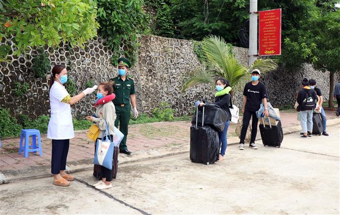 Các lưu học sinh Lào được kiểm tra thân nhiệt trước khi nhập cảnh tại cửa khẩu Chiềng Khương, tỉnh Sơn La. Ảnh: Hữu Quyết - TTXVN