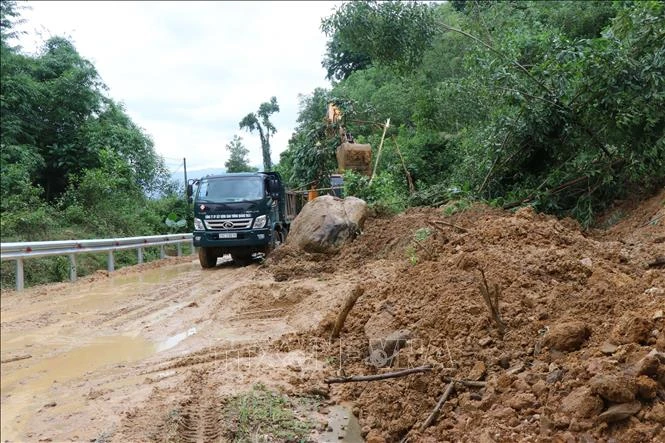 Khẩn trương dọn bùn, đất để người dân lưu thông trên đường tỉnh lộ 622B. Ảnh: Sỹ Thắng - TTXVN 