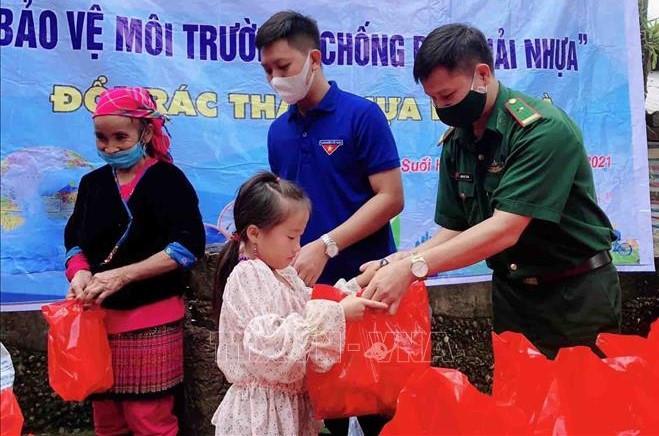 Lực lượng đoàn viên, thanh niên huyện Phong Thổ phối hợp với Đồn Biên phòng Sin Suối Hồ trao quà cho người dân, trẻ em khi đến đổi nhựa. Ảnh: Đinh Thùy-TTXVN 