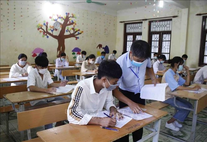 Giám thị hướng dẫn cho thí sinh điền thông tin cá nhân vào bài thi tại điểm thi Trường THPT huyện Phong Thổ. Ảnh: Đinh Thùy-TTXVN 