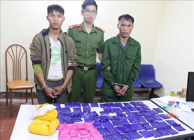 Hai đối tượng và tang vật tại cơ quan Công an. Ảnh: TTXVN phát