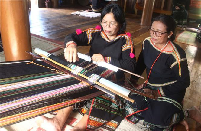 Bà H’Yam (phải), Giám đốc Hợp tác xã Dệt thổ cẩm Tơng Bông quan sát, hướng dẫn xã viên dệt thổ cẩm. Ảnh: Hoài Thu – TTXVN