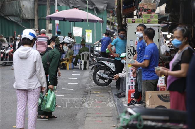 Người dân giữ khoảng cách khi mua hàng tại khu mua sắm hàng thiết yếu trên phố Nguyễn Thiện Thuật, quận Hoàn Kiếm (ảnh chụp sáng 26/7). Ảnh: Minh Quyết - TTXVN 
