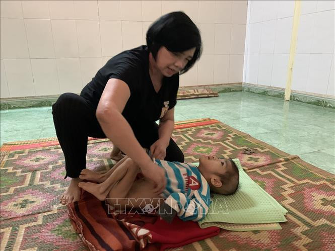 Bà Hồng chăm sóc cho trẻ khuyết tật. Ảnh: Quang Thái - TTXVN