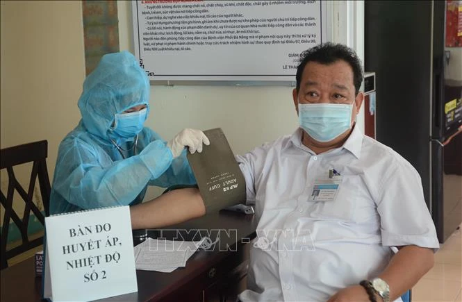 Nhân viên y tế khám sàng lọc cho người được tiêm. Ảnh: Văn Dũng - TTXVN 