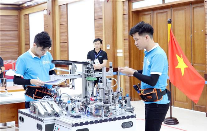2 thí sinh Đinh Tú Ngọc và Nguyễn Văn Tấn của đội tuyển thi nghề Cơ điện tử Việt Nam thực hiện bài thi của mình trong ngày 8/4/2021. Ảnh: Anh Tuấn – TTXVN