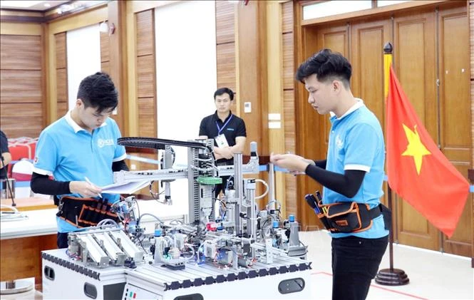 2 thí sinh Đinh Tú Ngọc và Nguyễn Văn Tấn của đội tuyển thi nghề Cơ điện tử Việt Nam thực hiện bài thi của mình trong ngày 8/4/2021. Ảnh: Anh Tuấn – TTXVN