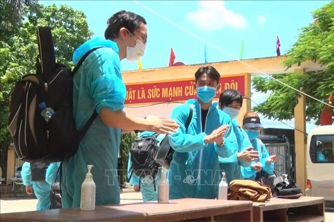 Các công dân tiến hành sát khuẩn khi vừa đến khu cách ly của Trung đoàn Bộ binh 126. Ảnh: Đinh Tuấn - TTXVN