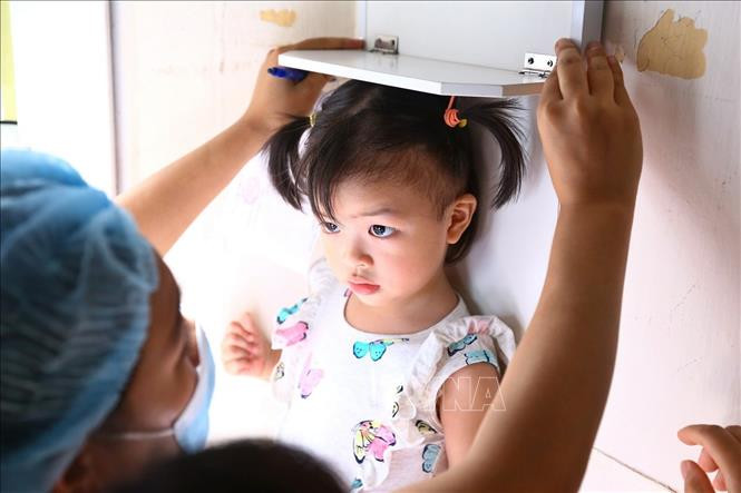 Trẻ em trong độ tuổi 6 – 36 tháng đến kiểm tra chiều cao, cân nặng . Ảnh: Minh Quyết – TTXVN